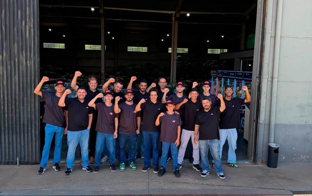 Equipe da M.Cruz Diversões reunida na entrada do galpão em Jaguapitã (PR), com o punho erguido